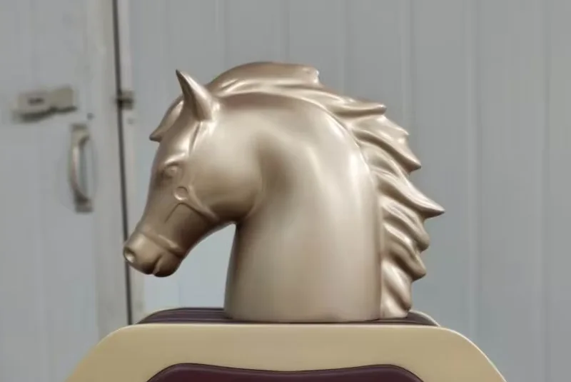 Front detail of a cast horse head cap showing mane plates, ear cavity, eye socket and bridle strap
