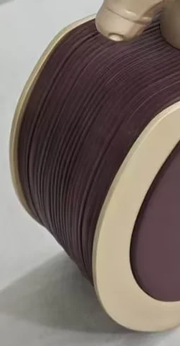 Close view of moulded vertical ribs on the curved flank of a burgundy factice bottle, ending at a pale gold edge band