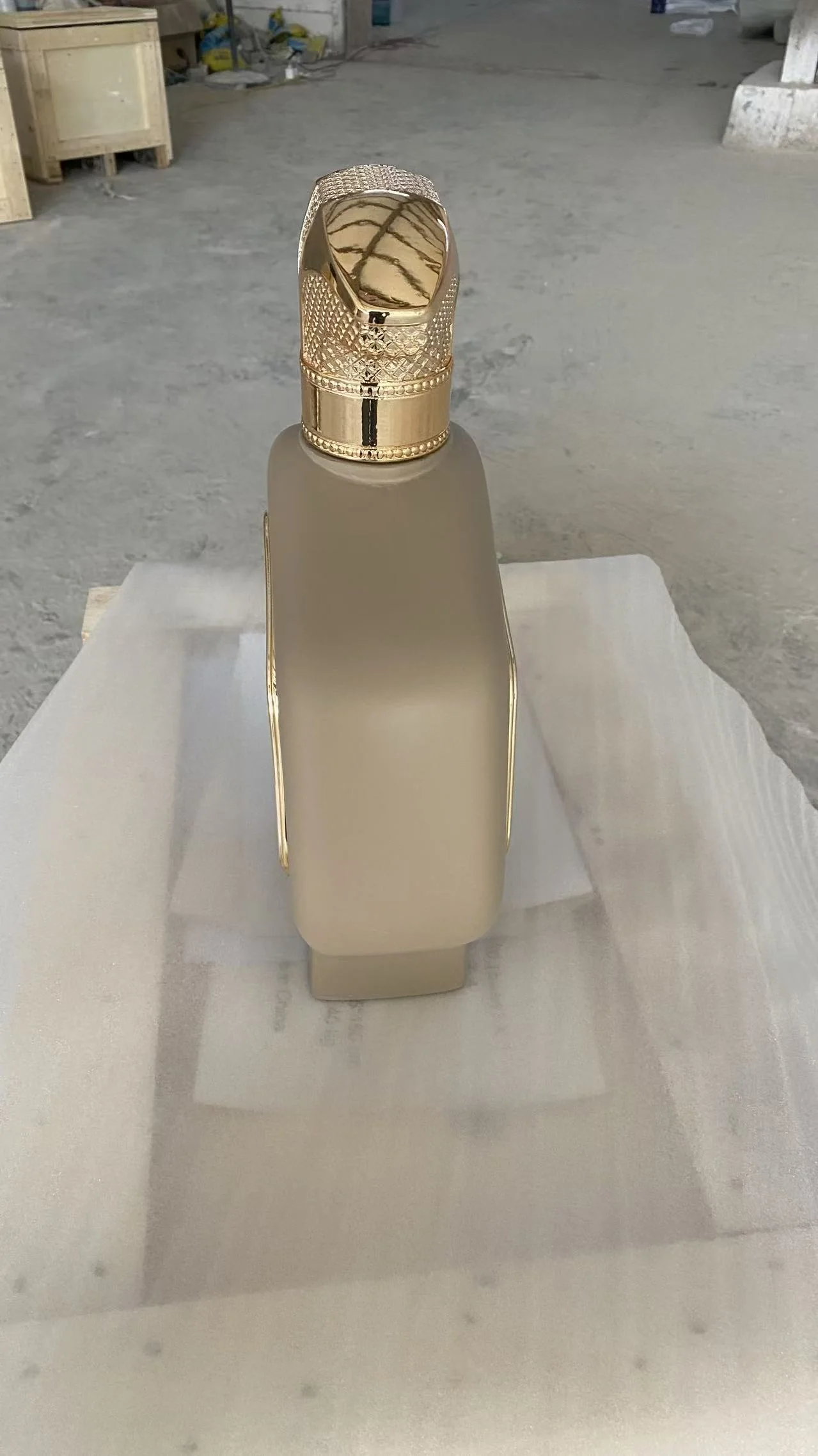 Rear workshop view of a large fiberglass perfume bottle display with a sculpted gold cap