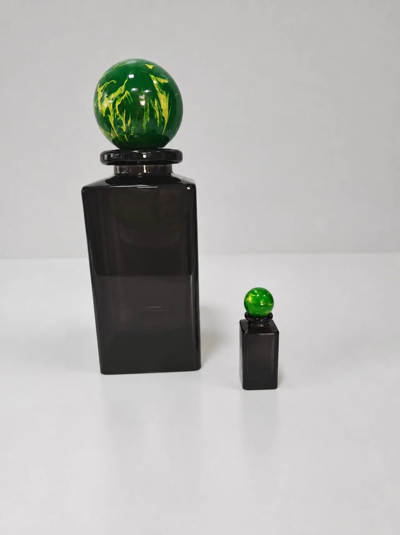 Dark brown translucent glass perfume bottle display models with green and yellow marble-pattern spherical caps