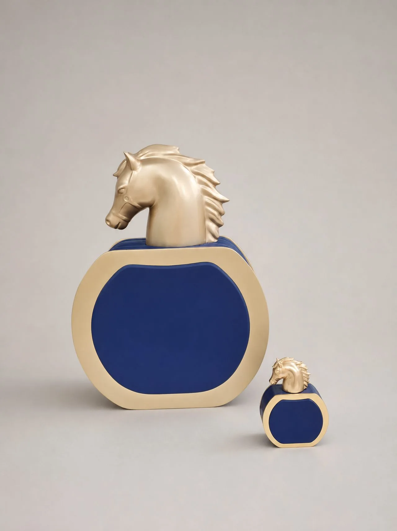 Matched pair of blue and gold perfume bottle display models with sculpted gold horse-head caps on a studio background